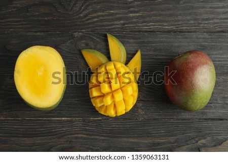 Cut ripe mangoes and space for text on wooden background, top view
