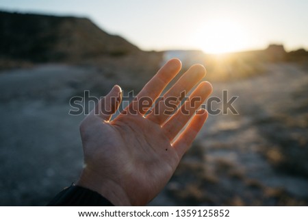 female hand  palm covers sunlight at sunset. beautiful sunny background. inspirational mood. 