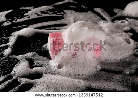 Soap foam with bubbles and sponge isolated on black background