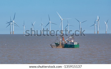 Off sure wind turbine and fishing boat Royalty-Free Stock Photo #135915137