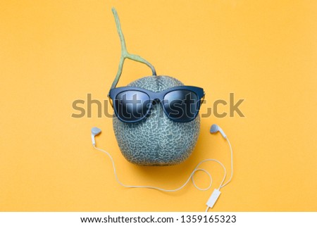 Melon with sun glasses and headphone on yellow background, summer theme