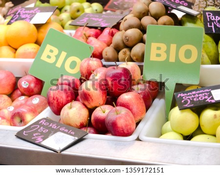Close up view of a stall in a bio market with different fruits, apples, kiwis, grapefruits and two green sign with ¨bio¨ which means organic in Spanish  written in white.