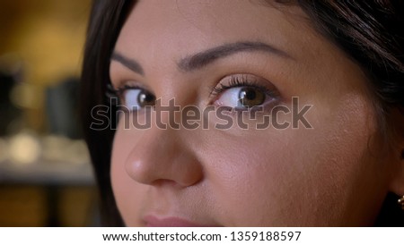 Close-up portrait in profile of beautiful middle-aged overweight woman watching calmly into camera on office background.