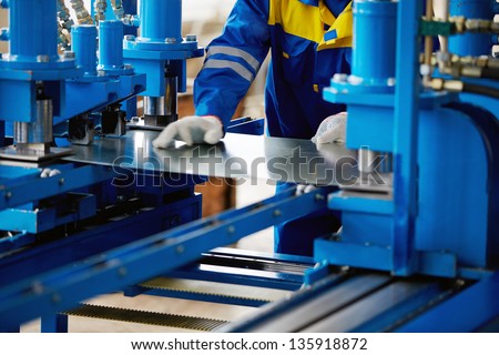 Sheet of metal and hands of worker who works on press Royalty-Free Stock Photo #135918872