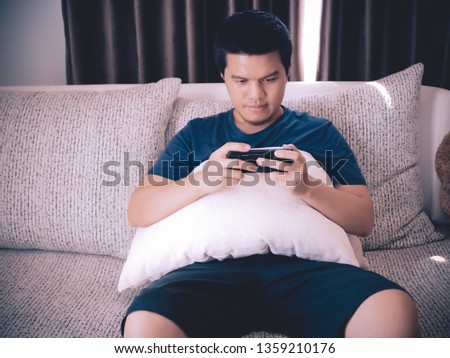 a men play game with smartphone on sofa at the house on holidays