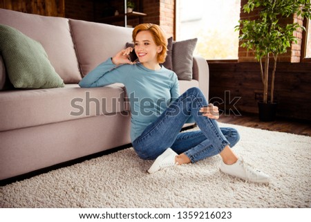 Close up side profile photo beautiful she her lady hand hold telephone ear tell say chatting wear blue pullover jeans denim clothes sit floor fluffy carpet divan sofa couch house living room indoors