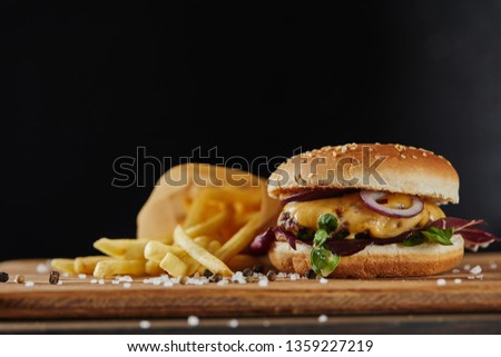 salt, french fries and delicious burger with meat on wooden surface isolated on black
