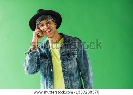 stylish mixed race man looking at camera, smiling and showing idea gesture on green screen