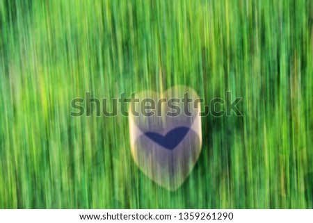 illustrated blurry heart shape sign and symbol on green grass lawn background