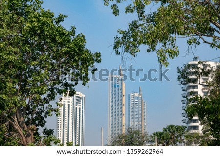 Green trees and skyscrapers in midtown on clear blue sky background