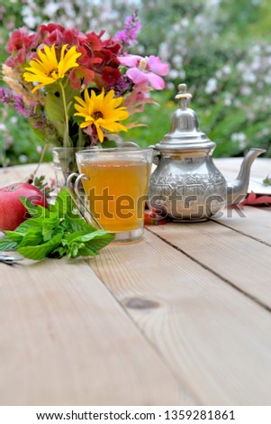 cup of mint tea with colorful bouquet of flowers on a table in garden