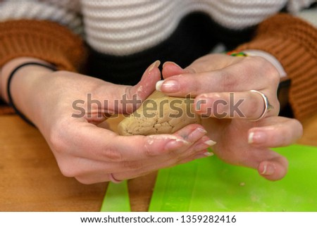 A sculpting class. Girl holds slice of clay and tries to give it form of.