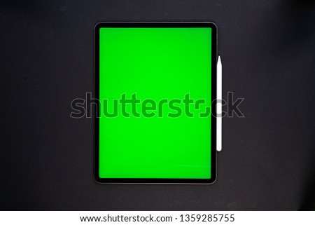 new tablet on a Black background with a keyboard and pen, and green screen top view