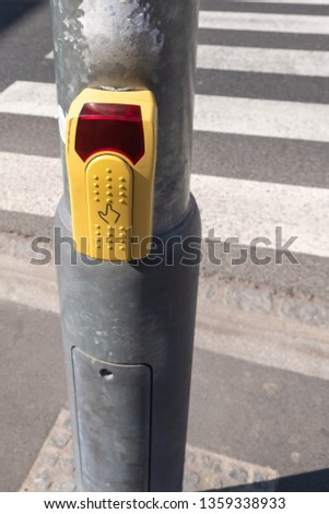 Yellow button with finger symbol at pedestrian crossing. 