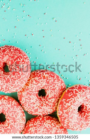 Five coral donuts lying in a corner. Donuts decorated with icing on blue background. Top view. Copy space for text.