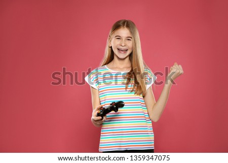Teenage girl playing video games with controller on color background