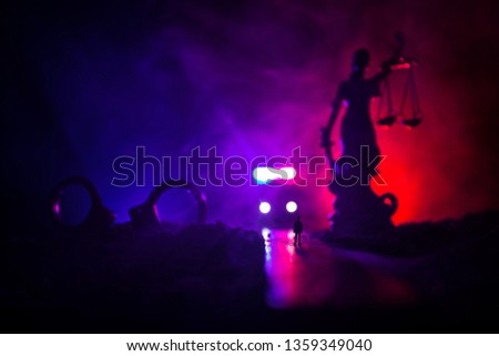 Legal law or crime concept. Man alone standing in the middle of the road on a foggy night. Artwork decoration with handcuffs, Statue of Justice and mallet of justice on toned foggy background.