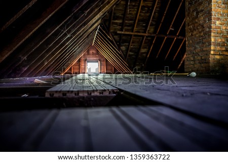 Old attic space with roof rafters and a window, shallow focus on wooden floor Royalty-Free Stock Photo #1359363722
