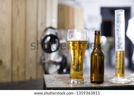 bottle and glass with beer on background of barrels for fermentation