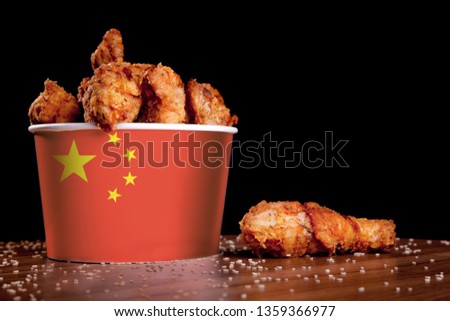 BBQ Chicken legs in bucket flag of China on a wooden table and black background.