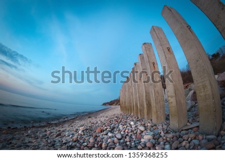 Concrete piles on the rocky beach of a Baltic sea at colorful sunset.