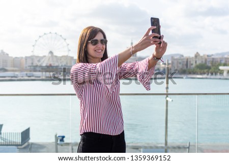 beautiful young woman making a selfie with her mobile phone in Malaga, a sunny day
