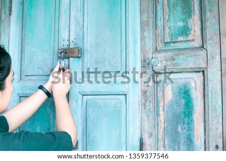 Women are unlocking the doors of old wooden houses that have a vintage green color.