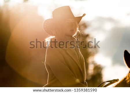 girl in a cowboy hat on a horse in the sun