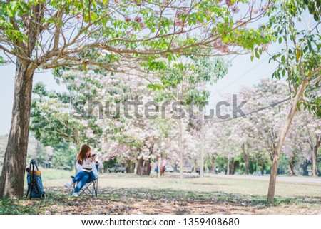 spring season with full bloom pink flower travel concept from beauty asian woman enjoy sit under the big tree with sight seeing sakura or cherry blossom with soft focus flower background