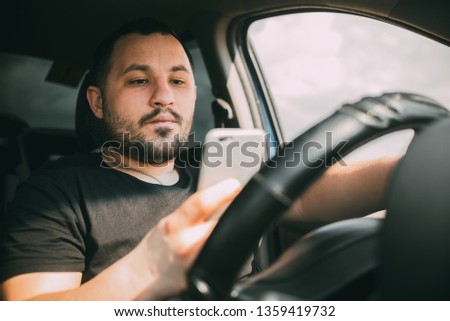 a man driving a car distracted by a smartphone creating an emergency Royalty-Free Stock Photo #1359419732