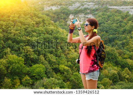 Image of brunette photographing mountain with vegetation