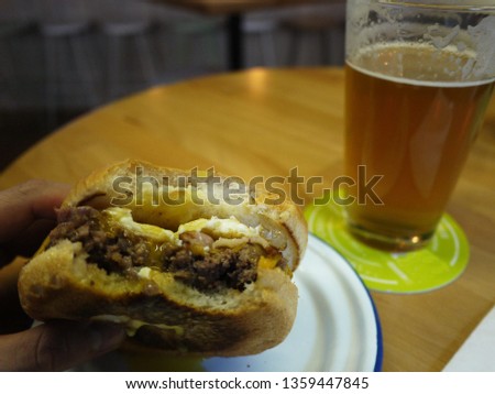 A glass of beer and a hamburger.