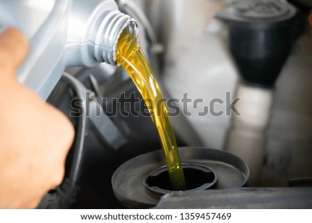 Pouring engine oil to car engine. Fresh oil poured during an oil change to a car.