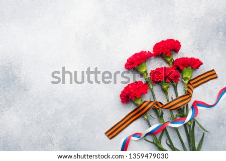 Red carnations and St. George ribbon on a concrete background. Symbol may 9, victory day. Copy space
