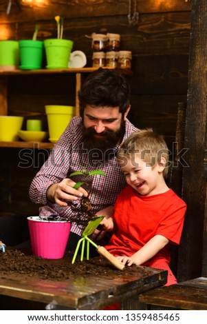 bearded man and little boy child love nature. happy gardeners with spring flowers. Father and son. Family day. Greenhouse. Flower care watering. Soil fertilizers. Work for you.