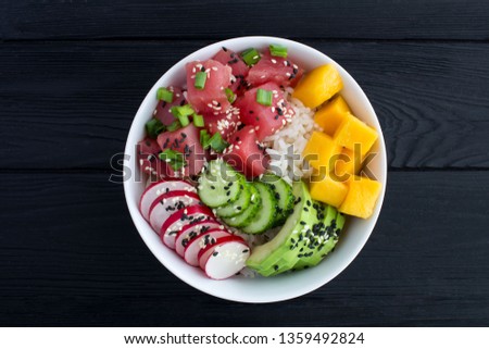 Poke bowl with tuna in the white bowl in the center of the black wooden background.Top view.Closeup.