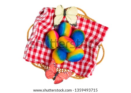 Happy easter decorations background. Top view of colorful easter eggs in a basket on red checkered napkin and two butterflies isolated on a white background. Beautiful decoration element.