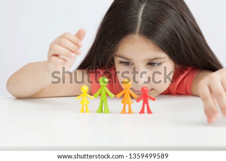 Happy traditional family figurines. A small child plays with colored plastic figures. Mom, dad, brother, sister, siblings. Family symbol. Adoption. Full family. Face out of focus. 