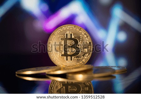 Bitcoin physical coin symbol with decreasing graph in the background