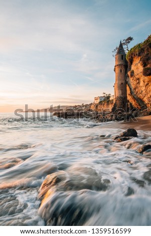 Waves in the Pacific Ocean and the Pirate Tower at sunset, at Victoria Beach, Laguna Beach, California