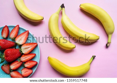 Strawberries with bananas on a pink background