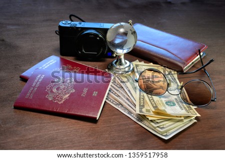 Sunglasses, a glass globe, passports, camera, notebook and money on a dark wooden background. Tourism concept.