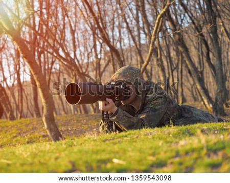 Wildlife, nature man photographer in camouflage outfit shooting, taking pictures