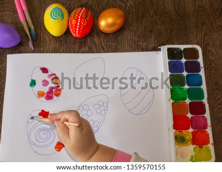 The girl draws. Children's drawing for Easter, painting eggs.
