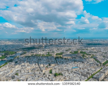 Panoramic aerial view of Paris, France from Eiffel Tower on a sunny day with famous landmarks and La Défense business district. Beautiful wide view of the capital of France, Paris with a cloudy sky.