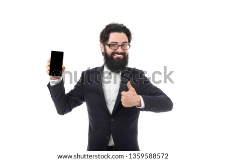 smiling bearded businessman with smartphone in one hand and showing like with other, isolated on white background