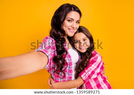 Close up photo two people funny brown haired mum mom small little daughter make take selfies daddy wait him his he home house miss wear casual pink checkered plaid shirts isolated yellow background