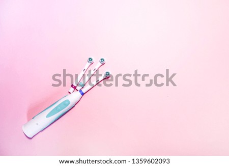 Two electrical toothbrushes on a soft light pink background.