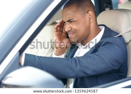 Young african american businessman driver sitting inside the car driving touching head having headache wrinkling unhappy side view in opened window close-up