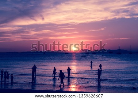 Pink toned. Sun path on the water of sea. Tropical island and sandy beach with silhouette of a lot of tourists. Enjoy of sunrise